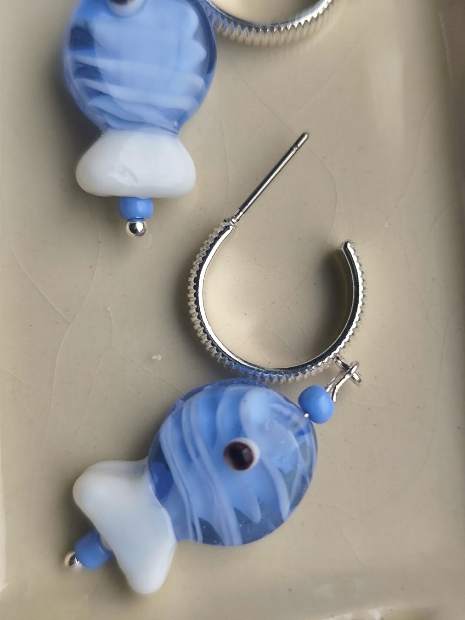 Zilverkleurige oorring met een schattige prachtig blauw visje.