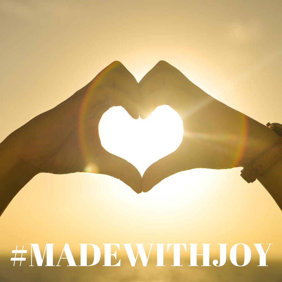 Handen die een hart vormen tegen de zon, met de tekst Made with Joy van Lakshmi