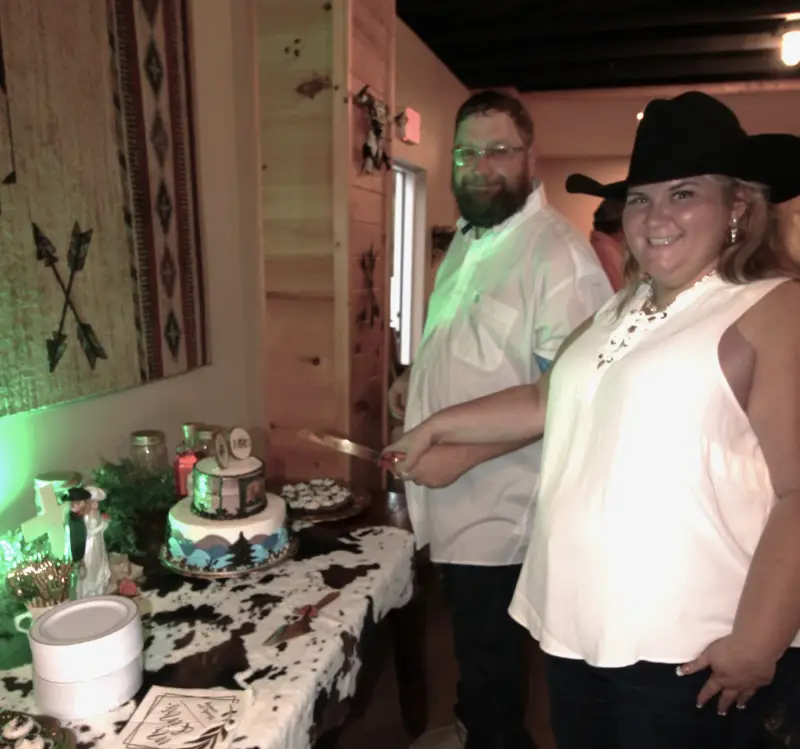 country-western-wedding-reception-rustic-wedding-cake-cutting-cowboy-hat-bride-mountain-themed-wedding-cake-standard.webp