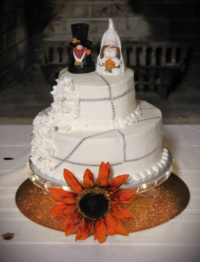 custom-made-two-tiered-wedding-cake-with-bride-and-groom-gnome-topper-white-piped-icing-roses-and-orange-sunflower-details-captured-by-tammy-brewer-photography-standard.jpg