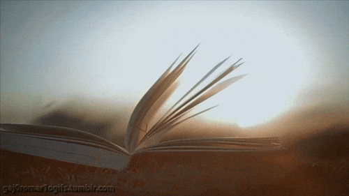 “Open book lying on grass with pages gently turning in the breeze.”
