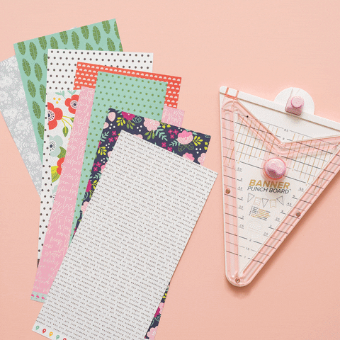 “Hands folding and cutting patterned paper with crafting tools, showing the handmade card‑making process.”