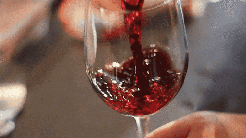 “Red wine being poured into a clear glass, symbolising romance and celebration for Valentine’s cards.”