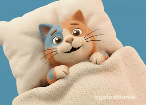 Cute sleepy cat tucked under a blanket, gently snoozing on a pillow.