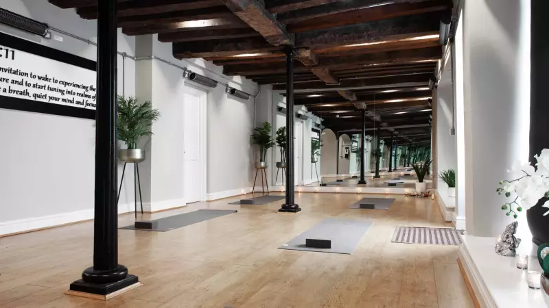 Inside 1111 yoga studio. Serene environment 2 black antique pillars. Grey yoga mats. Mirrored walls. Wooden flooring. Tidy neat and clean. A 