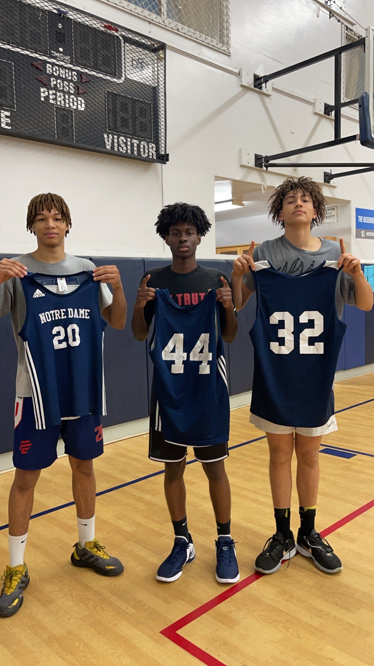 Basketball players holding up jersies