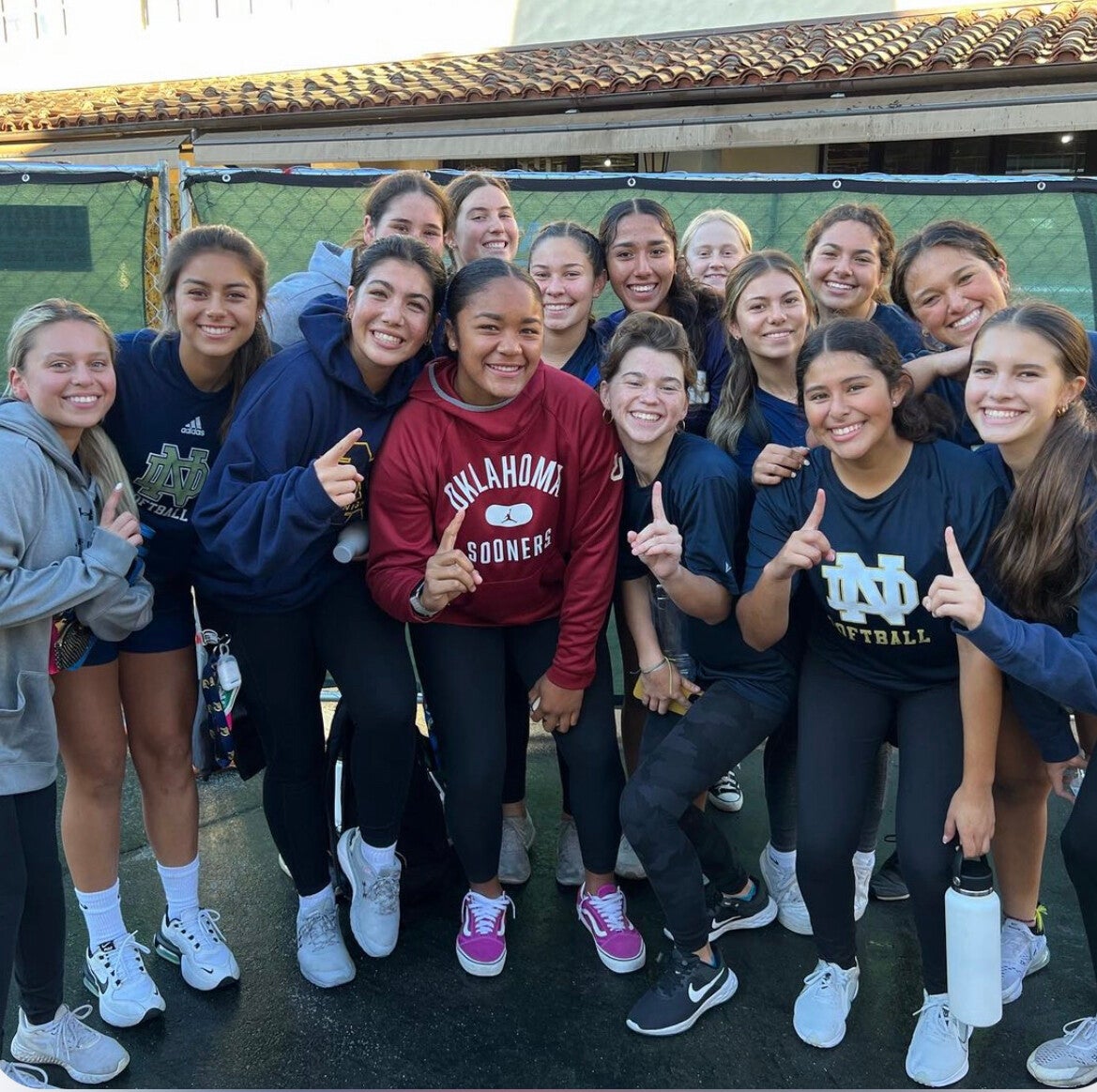 My softball team posing with our senior captain on her commitment day holding up #1's on our fingers