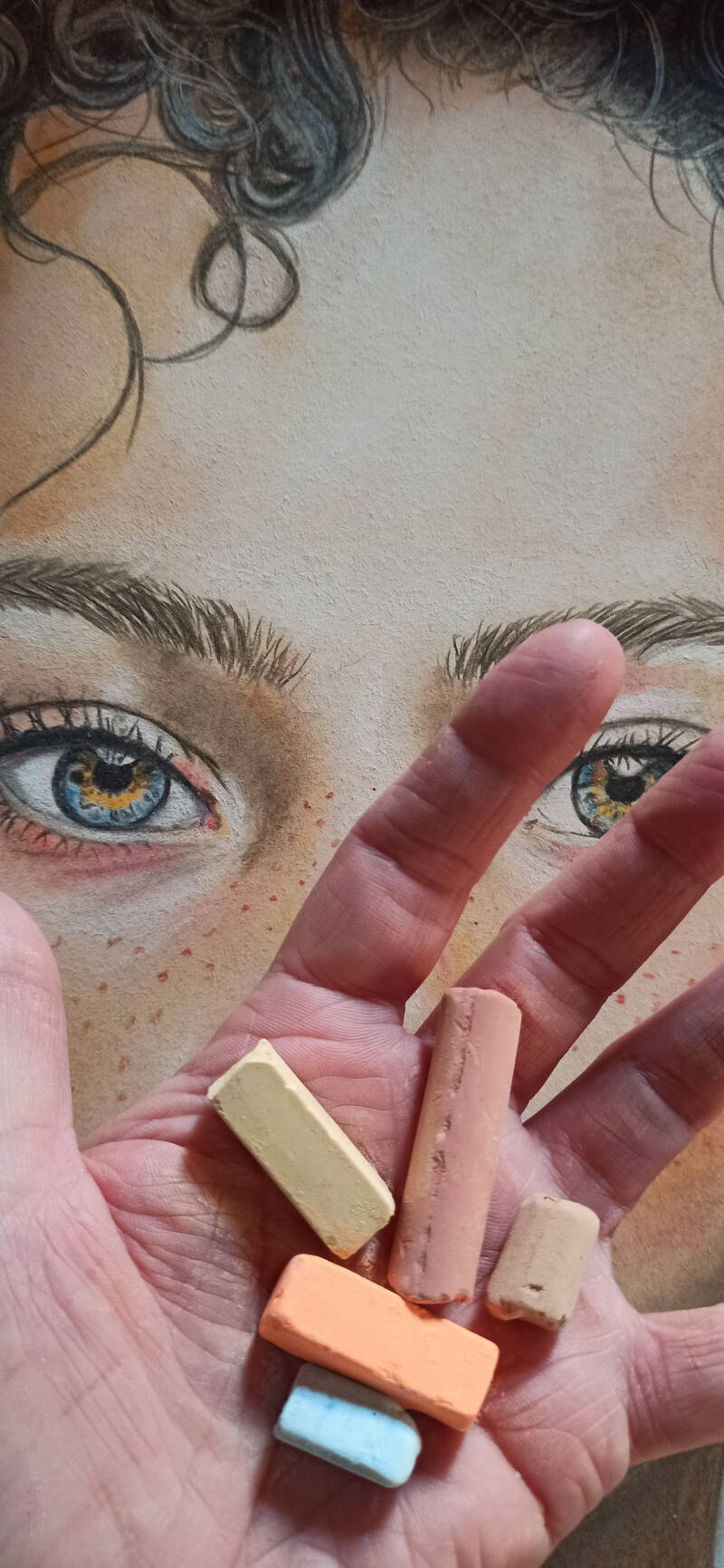 Dettaglio ritratto occhi azzurri realistico a pastello morbido - mano dell'artista con gessetti che sfuma iride e ciglia, opera Eleonora Sgura Art