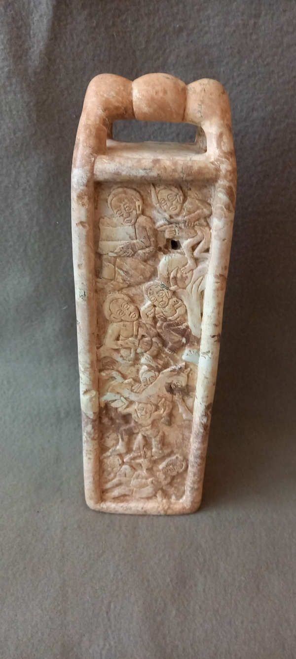 Versierd object in witte steen met religieuze voorstellingen.