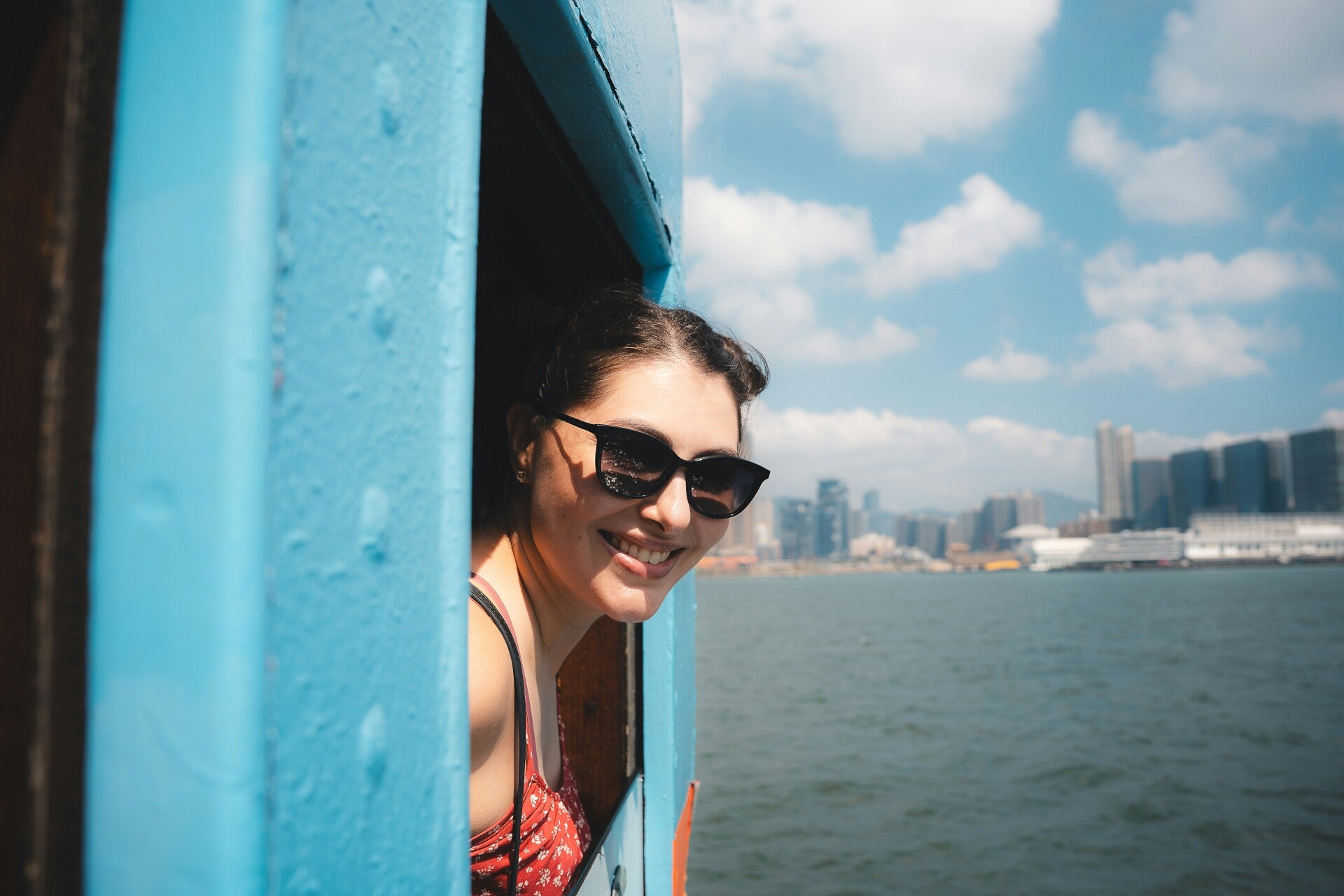Smiling woman looking out of a boat window representing travel and happiness.