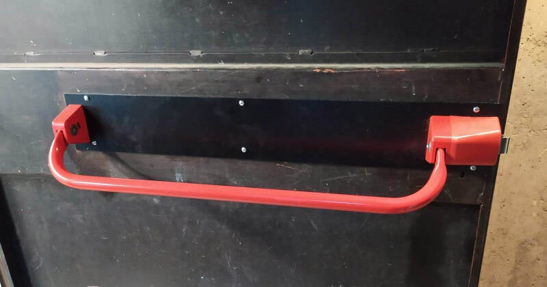 Barre anti panique fixée sur une porte de sortie de bâtiment 