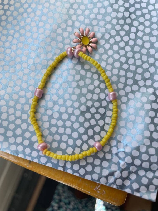 Armband geel met roze met bedel (bloem)