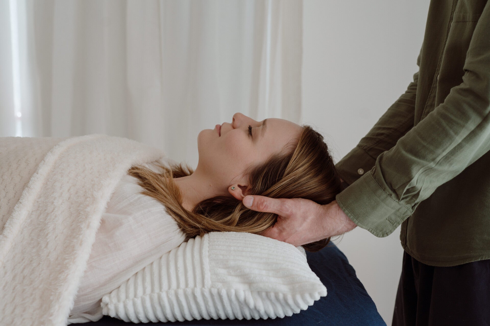 Practitioner providing Reiki and Seichem energy healing with hands supporting a client's head