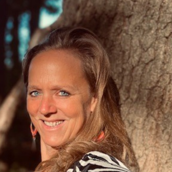 foto van Rebecca Bossaer die lachend tegen een boom leunt