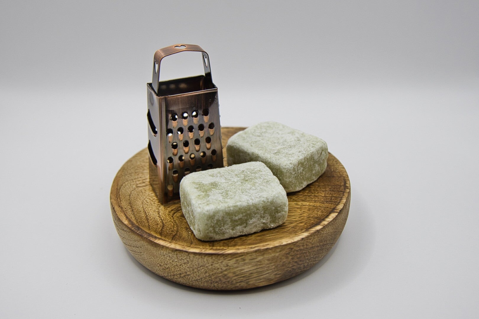 Houten schoteltje met amberblokjes en een bronze raspje