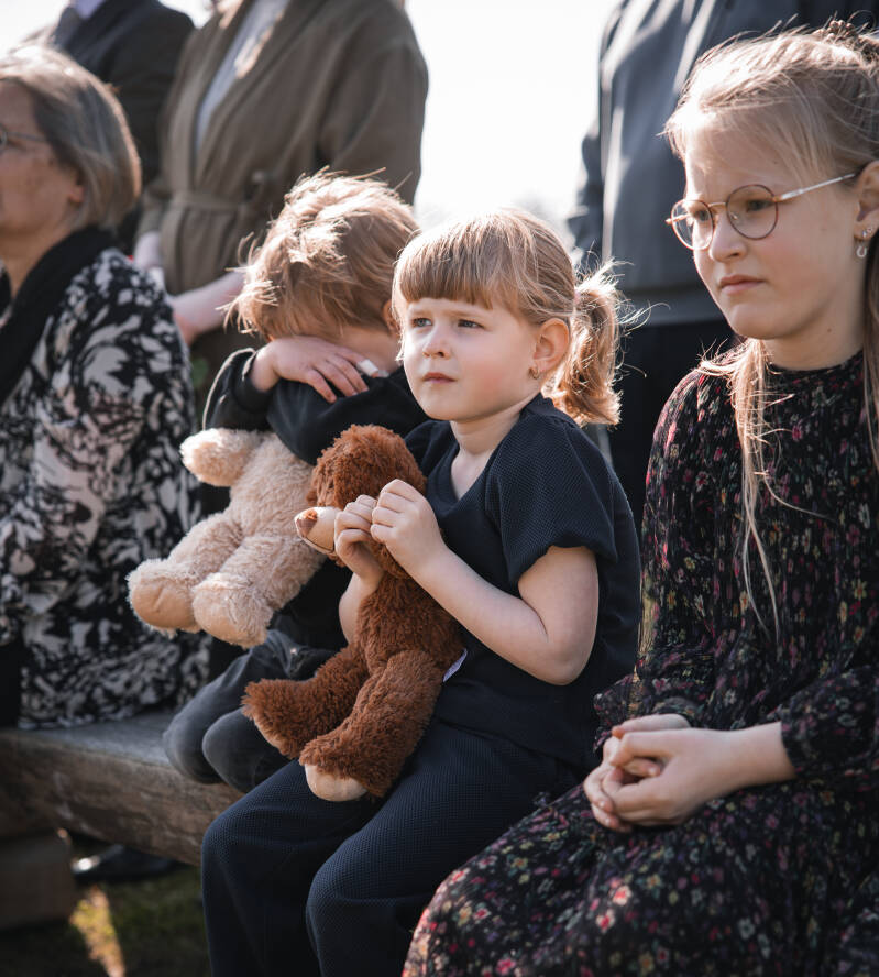 Twee jonge kinderen zoeken troost bij elkaar met een knuffelbeer tijdens een buitenuitvaart.