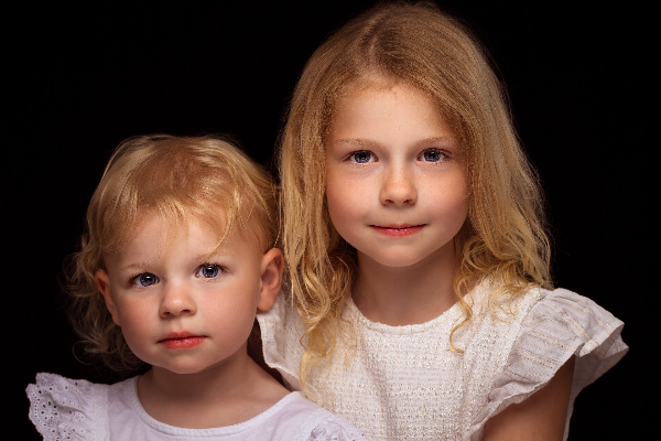 Kinderfortret twee zusjes zitten klaar voor de fotograaf, profesioneel kinderfotograaf