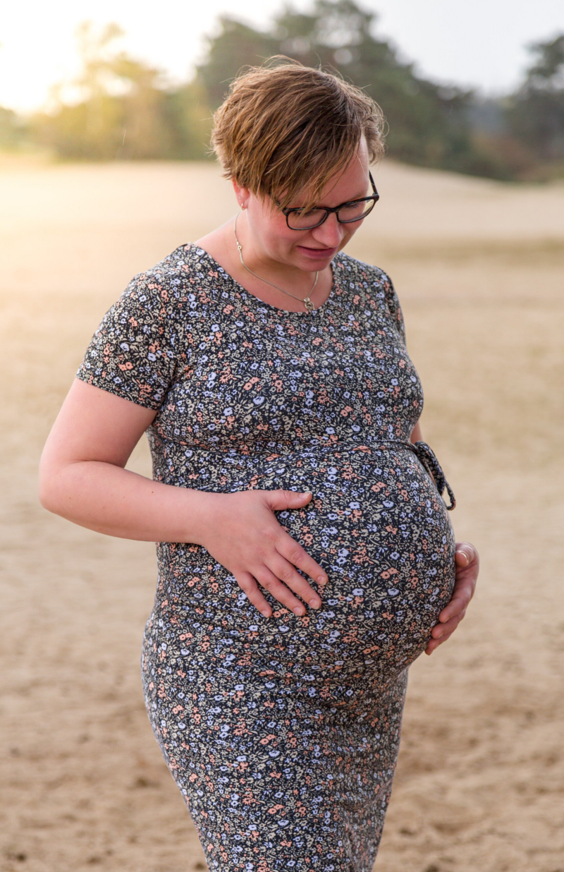zwangere vrouw kijkt naar haar buik en hou met bijde handen haar buik vast tarieven fotograaf gemaakt door Mark Nederhoed Fotografie