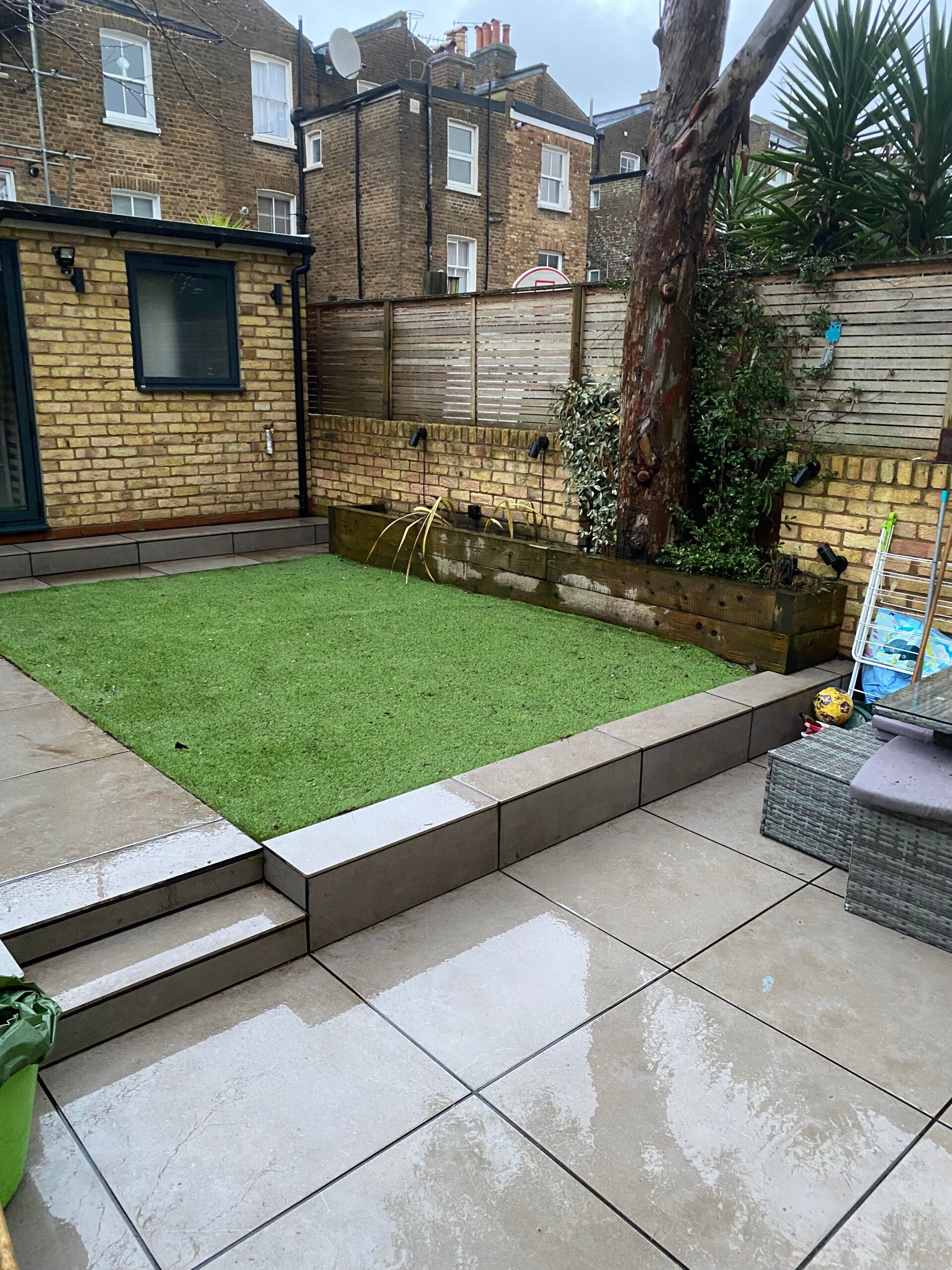 Cleaned garden terrace and stone path alongside a neat artificial grass lawn.