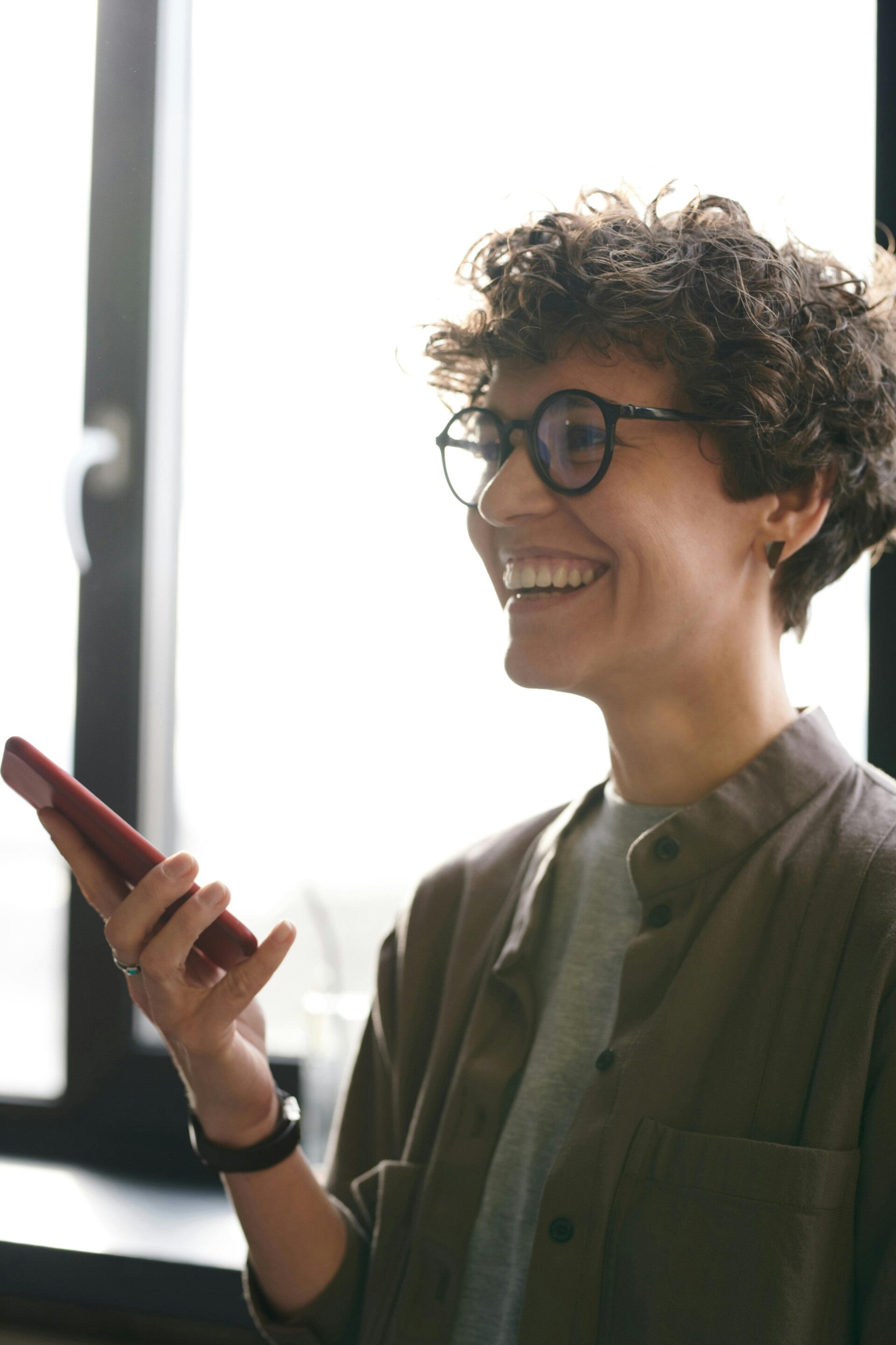 Smiling woman with glasses holding a smartphone