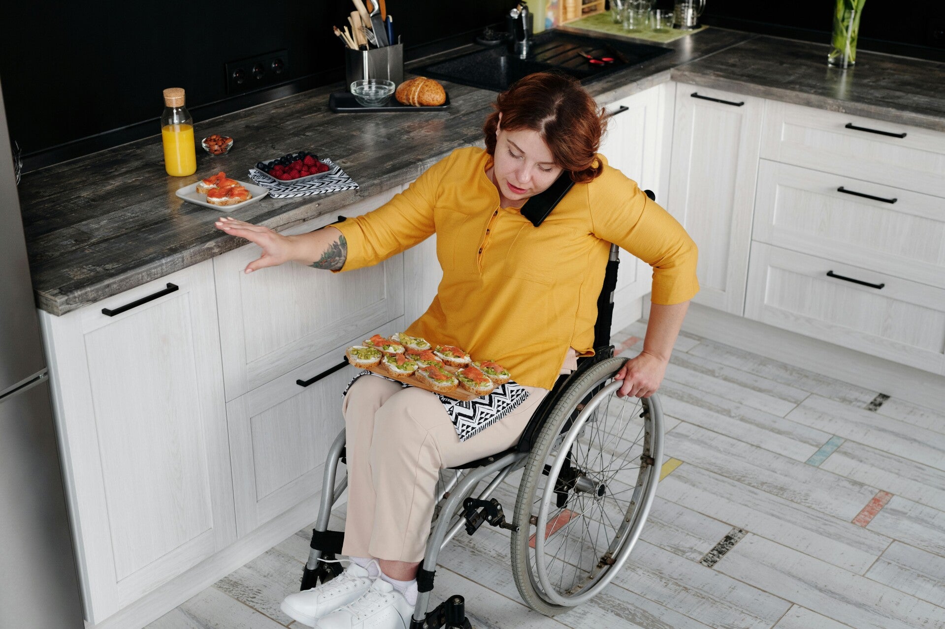 Woman in a wheelchair in a kitchen talking on the phone