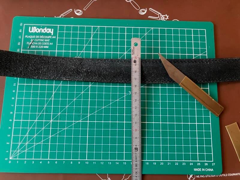 Découpe d’une bande de cuir au cutter pour fabriquer un strop maison