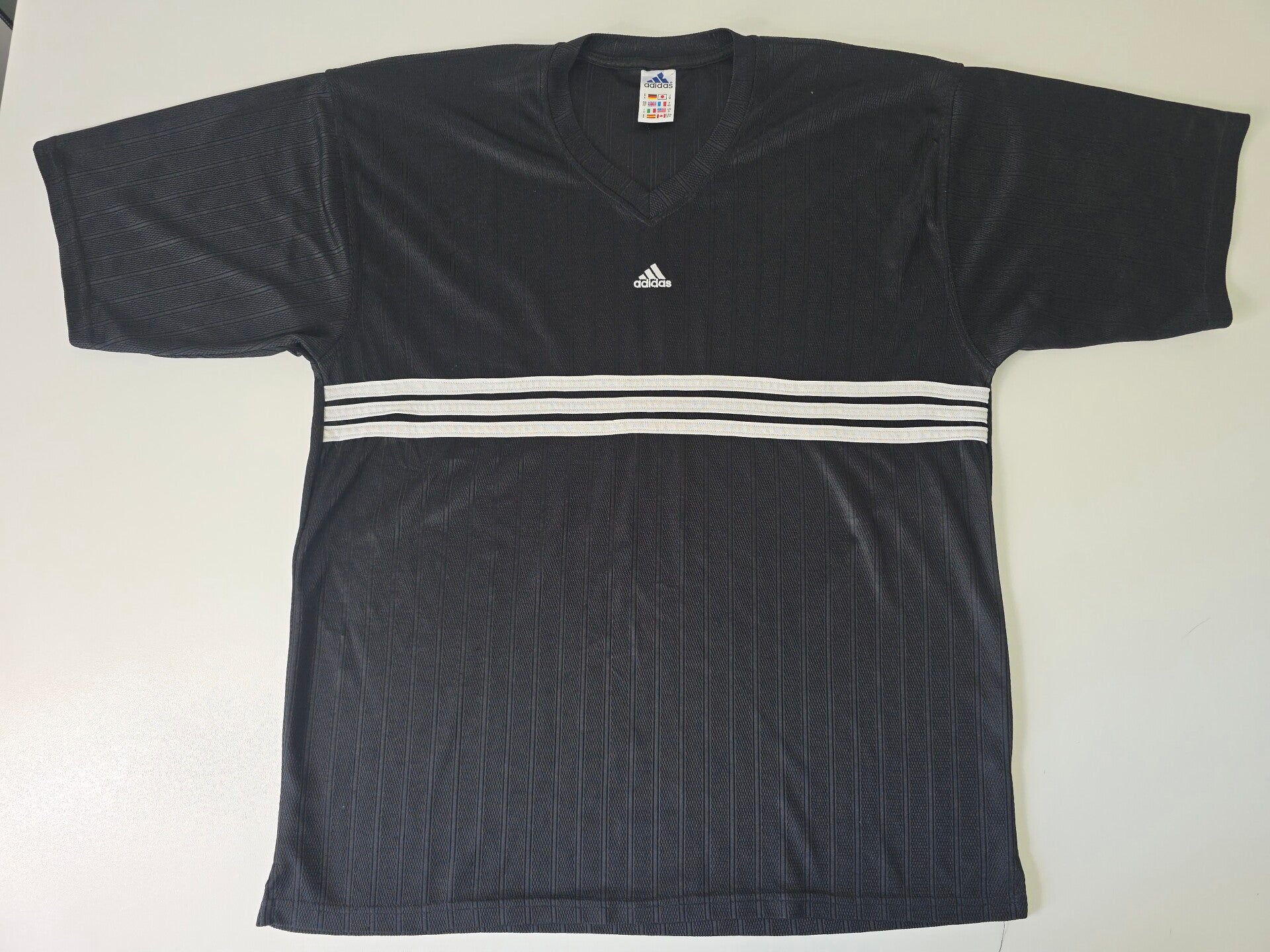 Vintage Adidas Sportshirt – Zwart   V‑hals • Subtiele strepen • 3‑Stripes detail. € 12,95