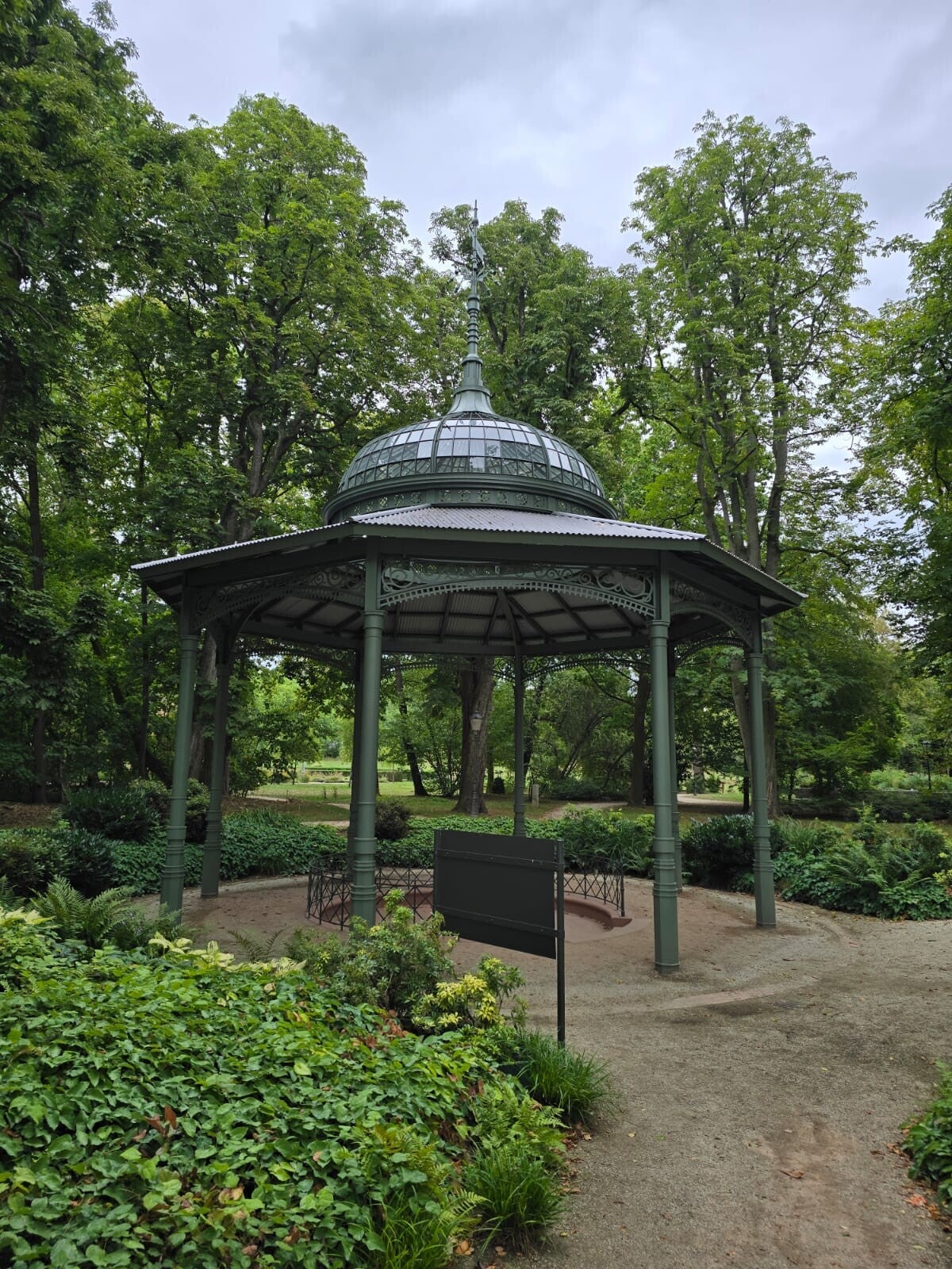 Historischer Pavillon umgeben von alten grünen Bäumen im Kurpark von Bad Homburg.