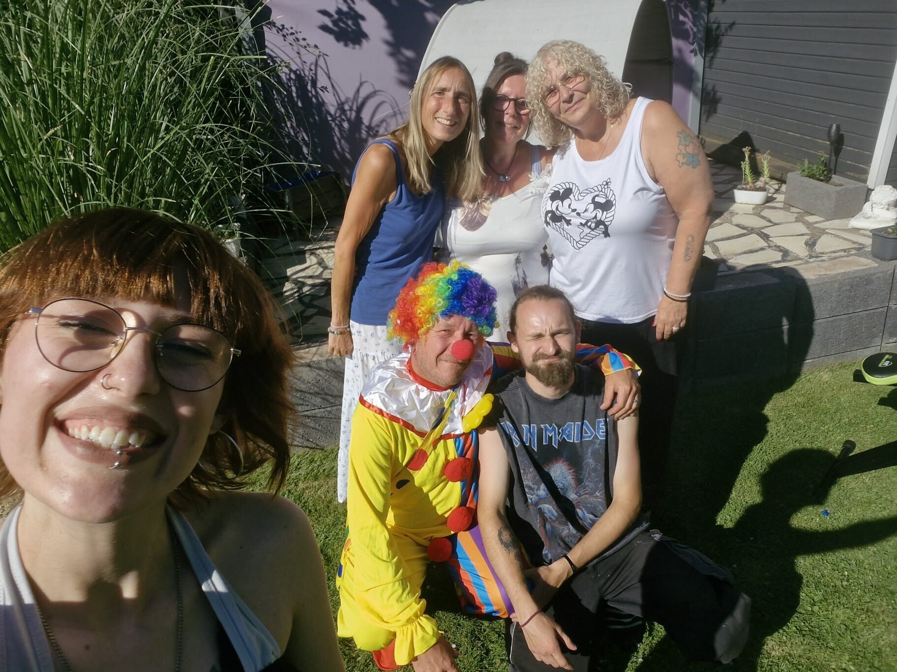 Freundinnen, Familie und Clown bei einem gemeinsamen Herzensmoment im Garten