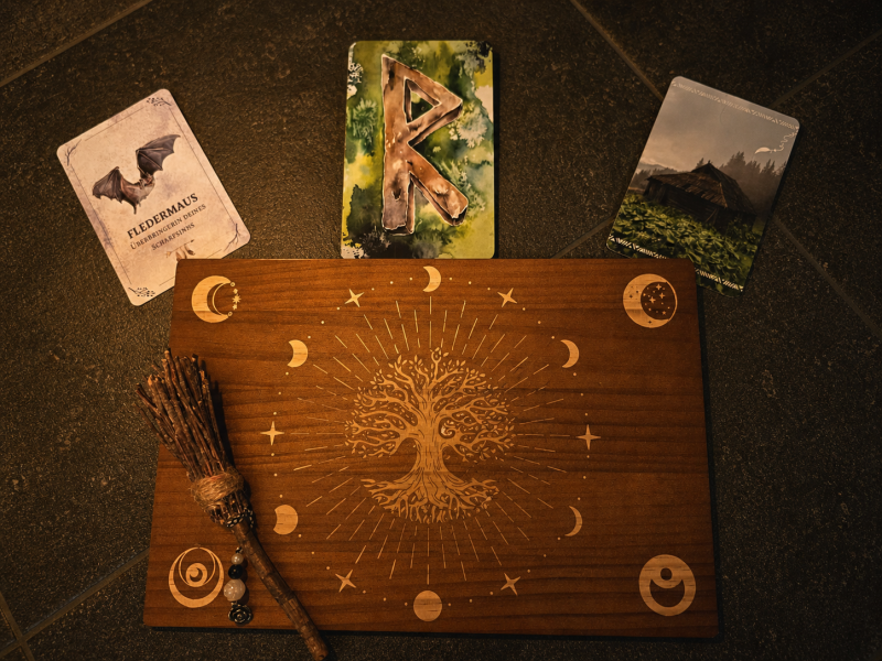 Spirituelle Kartenlegung mit Fledermauskarte, Rune Raidoho und Holzaltar mit Ritualbesen und Lebensbaum