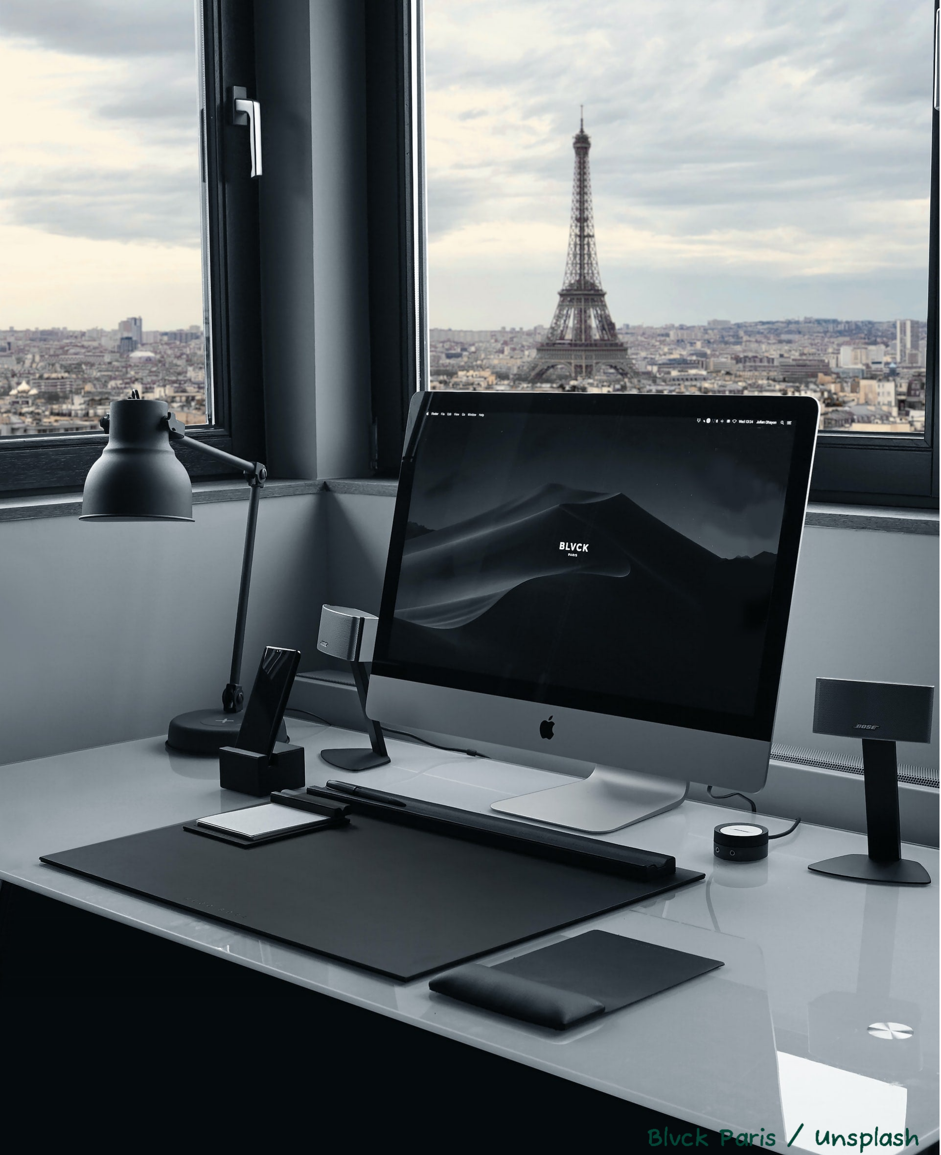 photo d'un bureau avec un ordinateur avec la vue sur  la tour Eiffel à Paris.