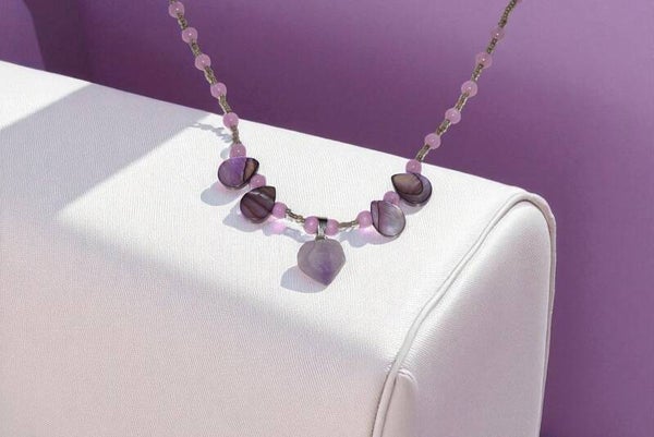 Collier 43 cm + extension 5 cm, composé d'un pendentif en améthyste, de perles en nacre violettes, de perles en oeil de chat roses et de perles de rocaille multicolores. Acier inoxydable