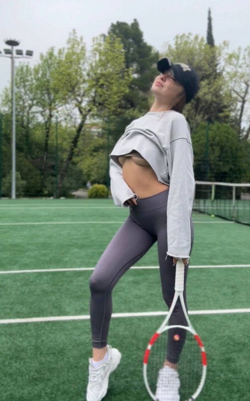 Brünettes Fitness Model Selina Deluxe als Personaltrainerin im Sportstudio mit langen Haaren und trainierter Figur