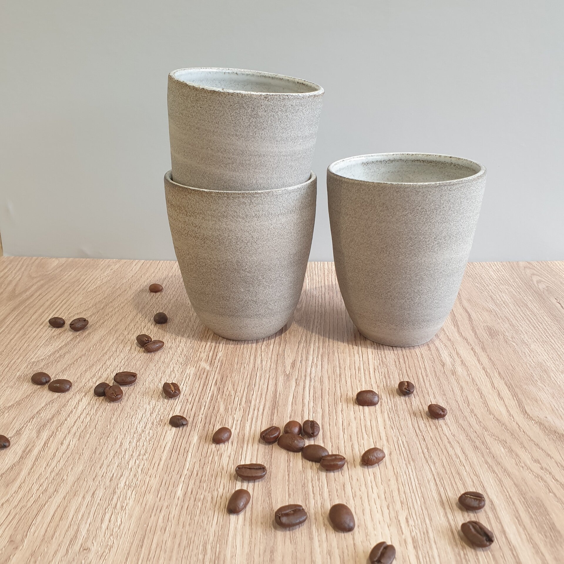 Grijskleurig kopje ongeglazuurd aan de buitenzijde, wit glanzend binnenkant.