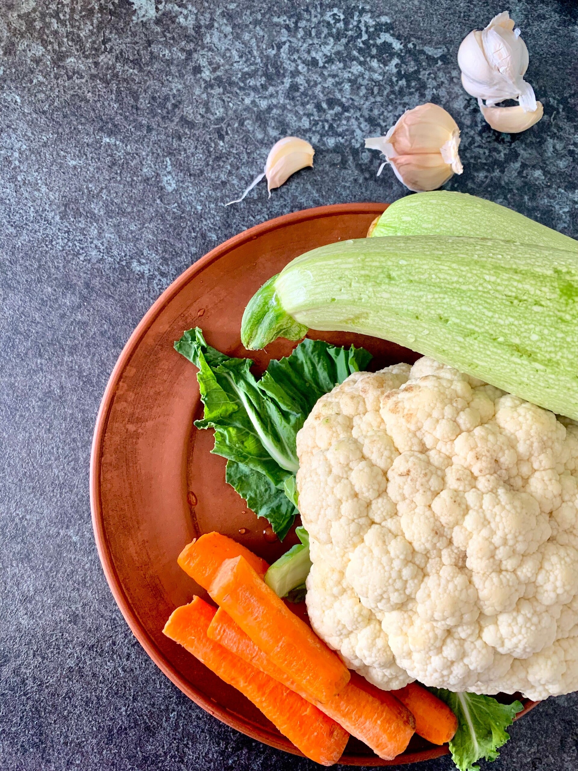 Een bord gevuld met courgette, bloemkool en wortelen voor een afslanksoep.