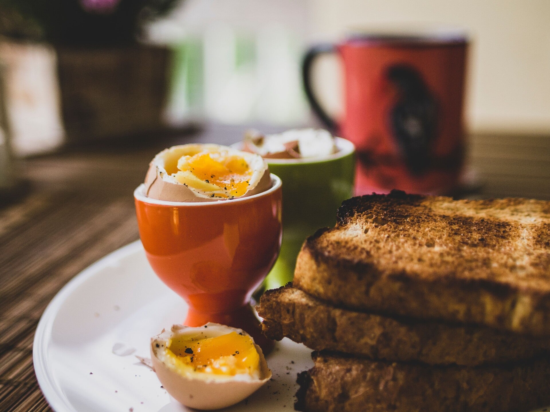 Bord met geroosterd brood en zachtgekookt eitje met een tas koffie.