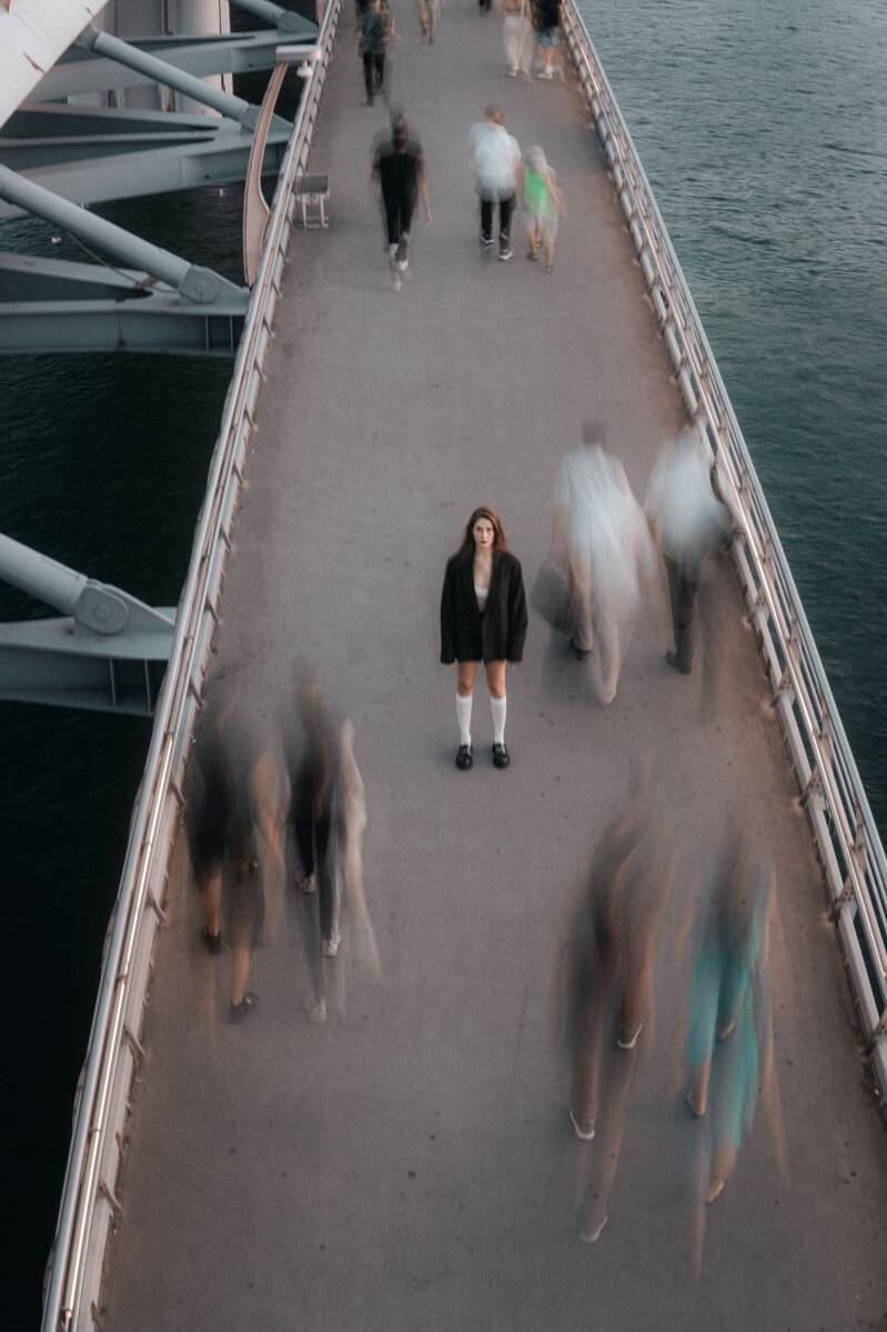 Eenzame vrouw tussen mensen op een brug.