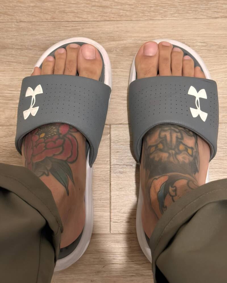 Beautiful man's big tattooed feet up close in slides.