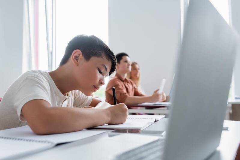 Calm and focused teenage boy studying at a desk in a modern learning environment, representing emotional resilience, concentration, confidence, and academic wellbeing for young men.