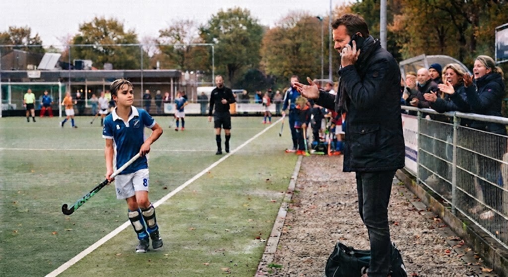 hockeyvader die geen aandacht voor zijn zoon heeft en steeds staat te bellen