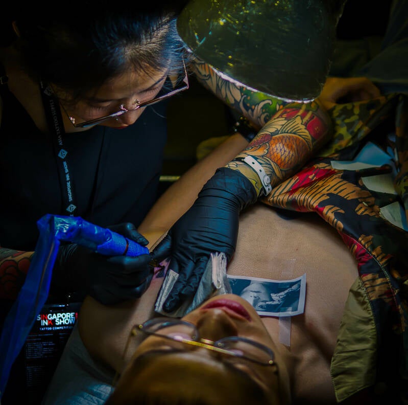 Korean tattoo artist Yeono is tattooing a portrait during the Singapore Ink Show