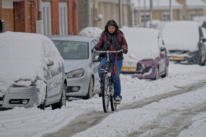 A girl is riding a bycicle in heavy snow fall in The Netherlands on January 4th 2026