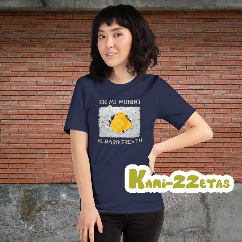 Mujer sonriendo con camiseta "En mi mundo el raro eres tú" (mano rompiendo muro), luciendo un estilo desenfadado.