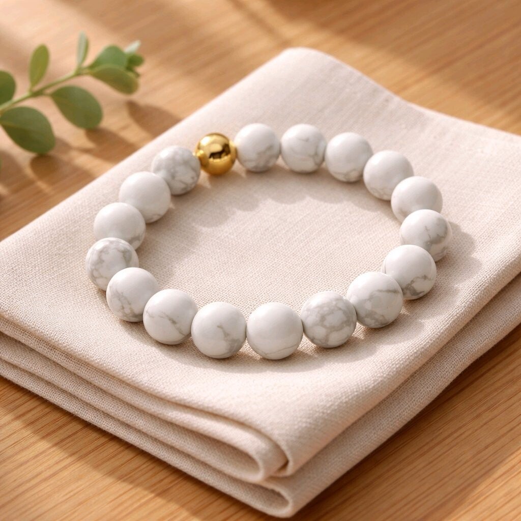 Bracelet en perles semi-précieuses de Howlite. Perle en acier inoxydable dorée. Fil élastique. 10 mm