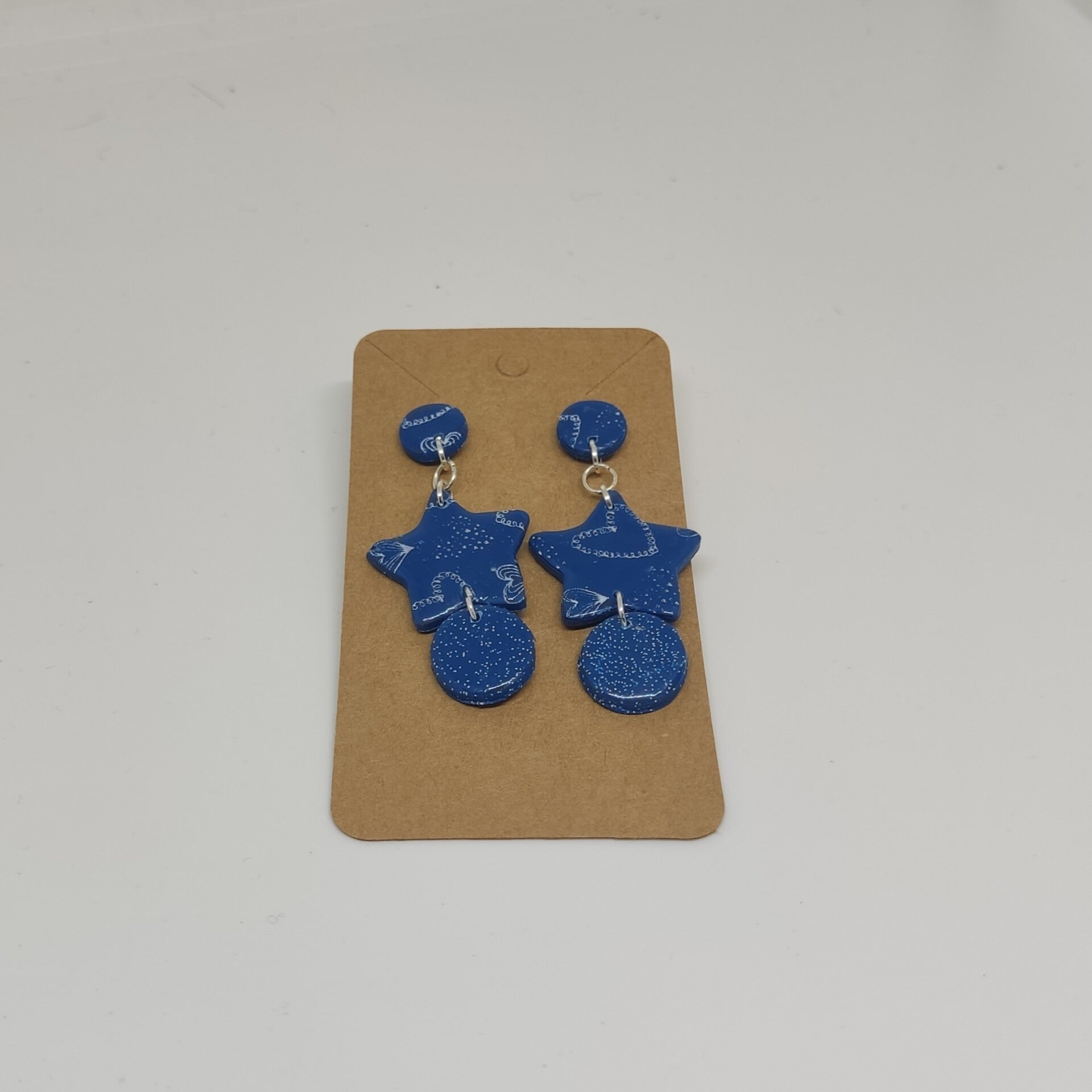 Oorbellen stervorm blauw met witte opdruk hartjes