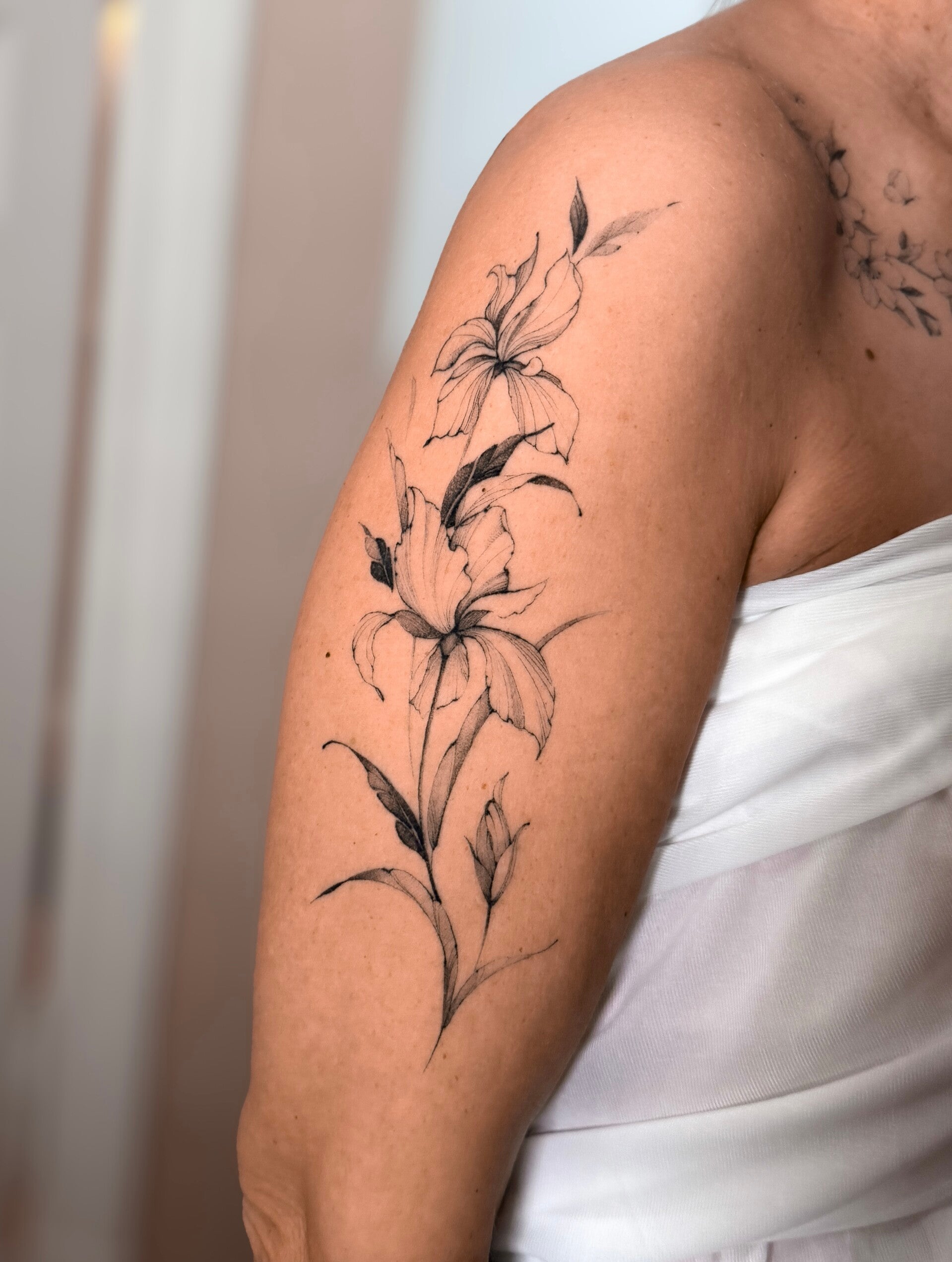 minimalistyczny tatuaż kwiatowy na ramieniu Olsztyn