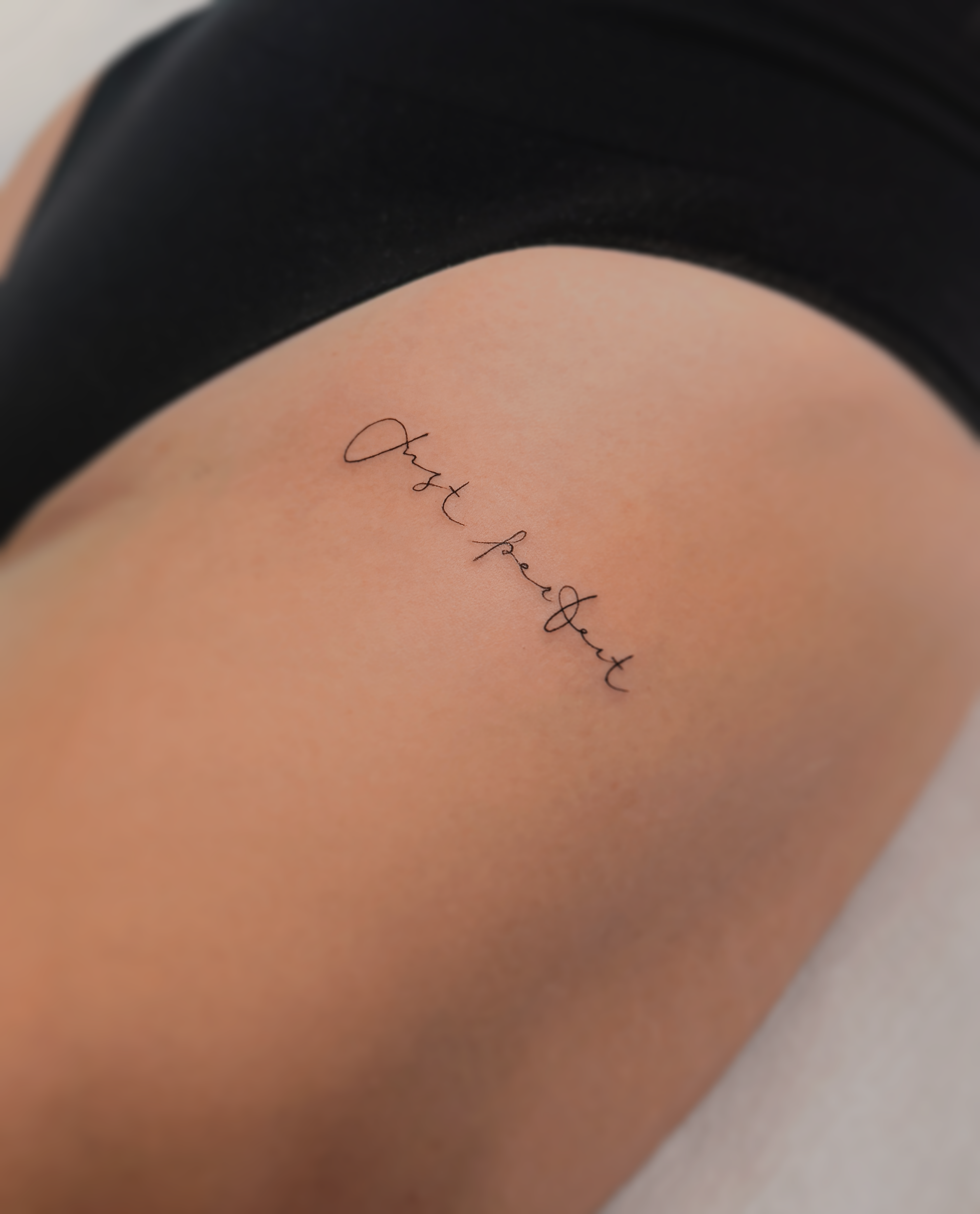 subtelny tatauaż napisa na udzie Olsztyn 