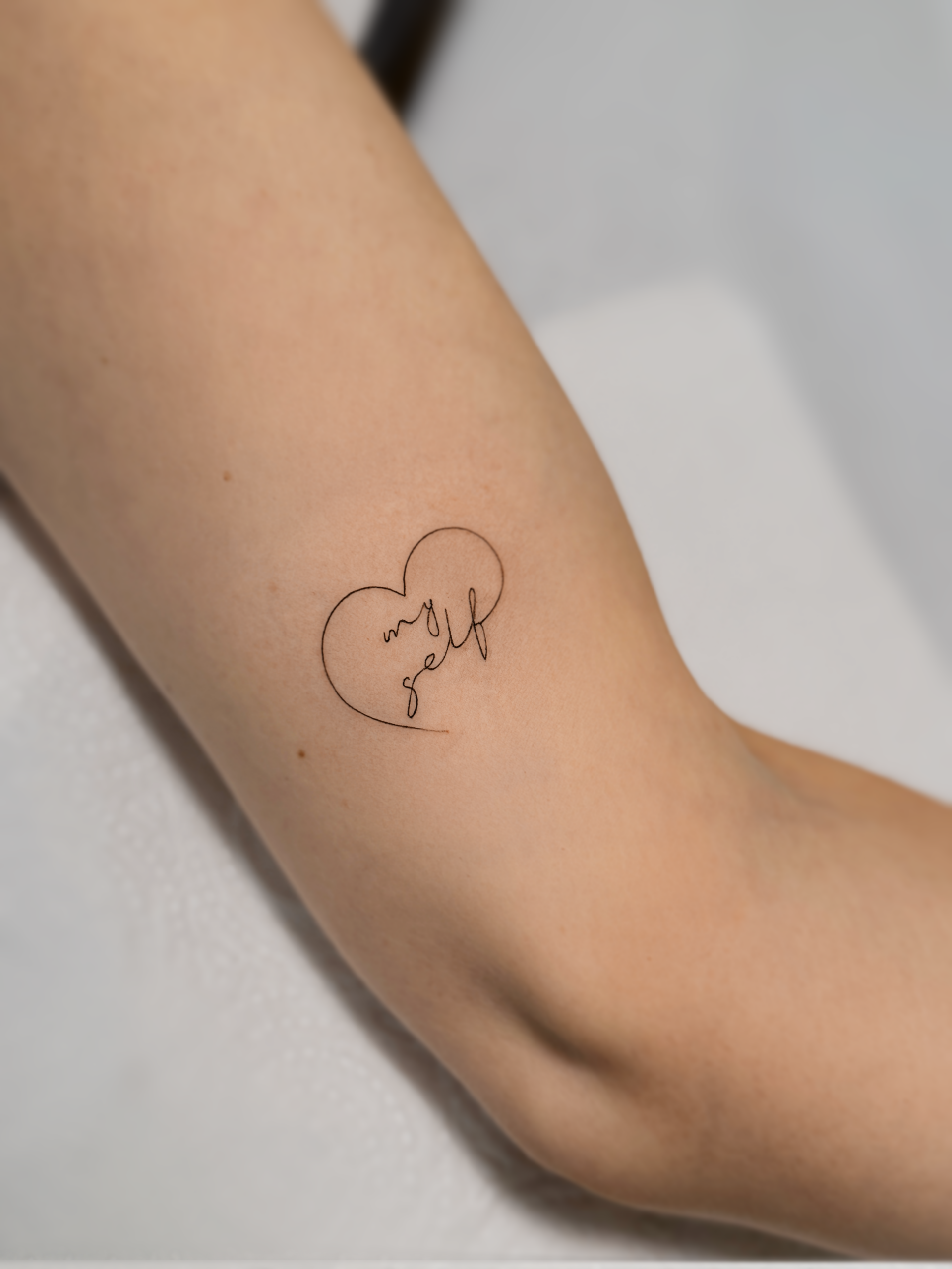 minimalistyczny tatuaż napis w stylu fine line serduszko na ręku Olsztyn 