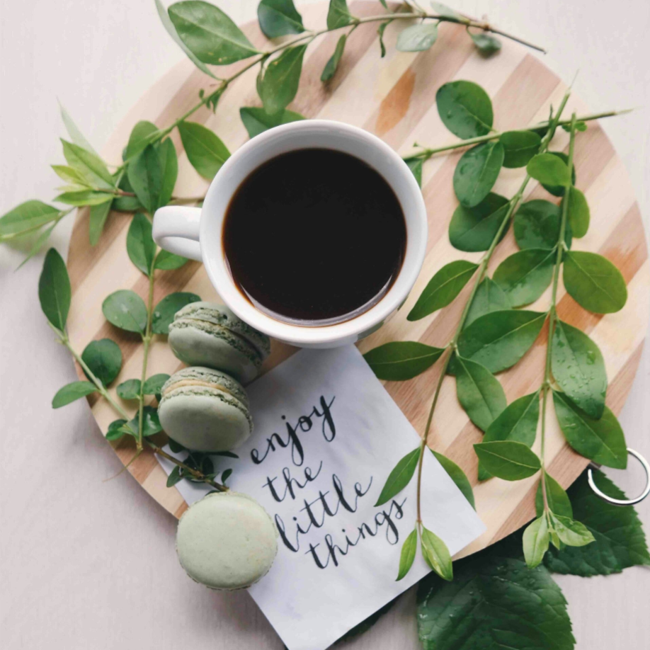 Schön dekorirte Teller mit Keksen, Laubzweigen und einen Kaffe und Zettel mit Aufschrift: enjoy the little things