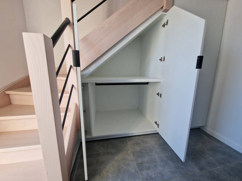 Op maat gemaakte opbergkast onder de trap, wit afgewerkt met open legplanken